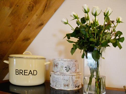 a table with a vase of flowers and a candle at Meadow Mews in Chillington