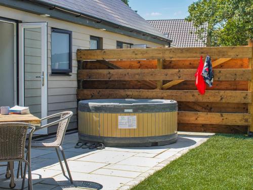 a wooden fence with a hot tub next to a table and chairs at No 1 Fox Burrow-Uk44306 in Lenwade