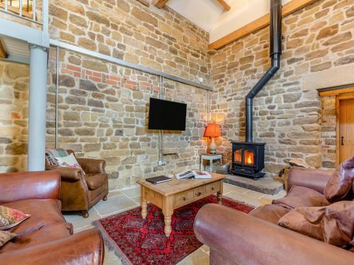 a living room with leather furniture and a stone wall at The Gin Gang in Whorlton
