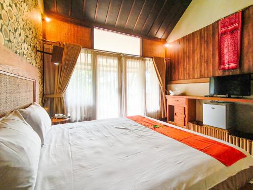a bedroom with a large bed and a television at The Lavana Green Asri Cottage in Senggigi