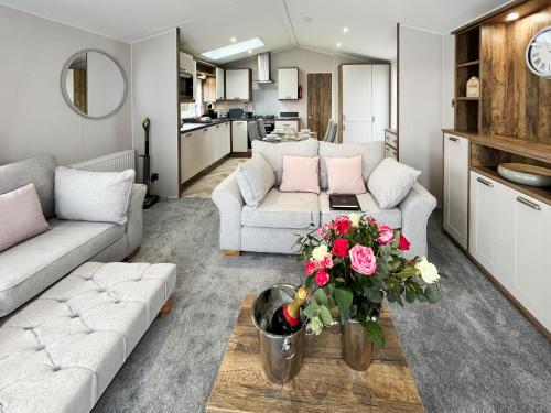 a living room with two couches and a table with flowers at Reed Roost - Uk37726 in Skegness