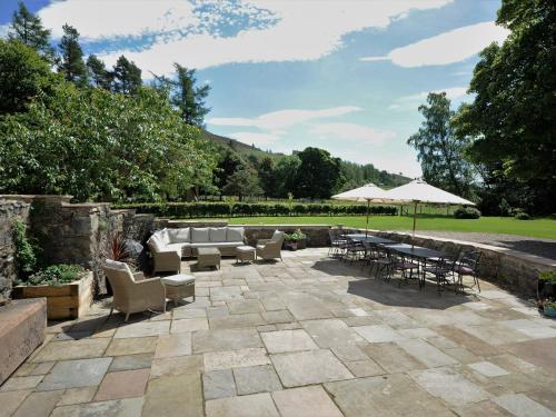 a patio with chairs and tables and an umbrella at Cray House - Ukc4632 in Glenshee