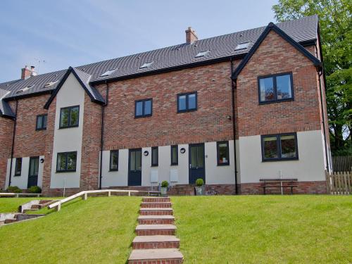 a large brick building with a grass yard in front of it at Salar's Rest - 28028 in Alnmouth