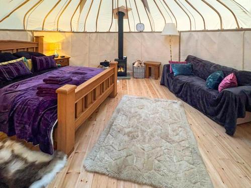 a room with a bed and a couch in a yurt at Ember Sky Yurt - Uk51679 in Beadnell