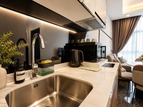 a kitchen with a sink and a living room at Royce Residence KLCC by Dormeo Destinations in Kuala Lumpur