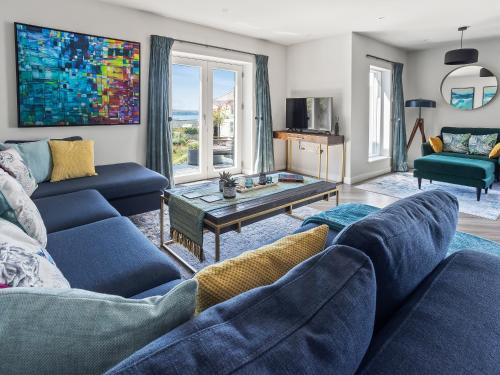 a living room with two blue couches and a table at Seaglass in Mortehoe