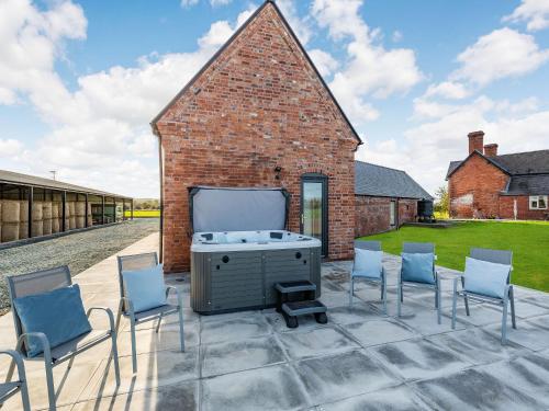 a patio with chairs and a grill in front of a brick building at Buckley Farm, Barn 1 - Uk36588 in Oswestry