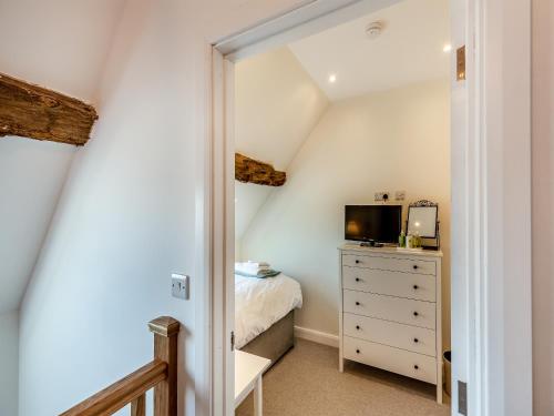 a bedroom with a bed and a dresser with a television at Buckley Farm, Barn 1 - Uk36588 in Oswestry