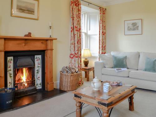 a living room with a couch and a fireplace at Islabank Farmhouse - Saap in Kirkton of Airlie