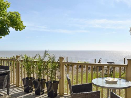 a patio with a table and chairs and the ocean at Seacliff in Corton