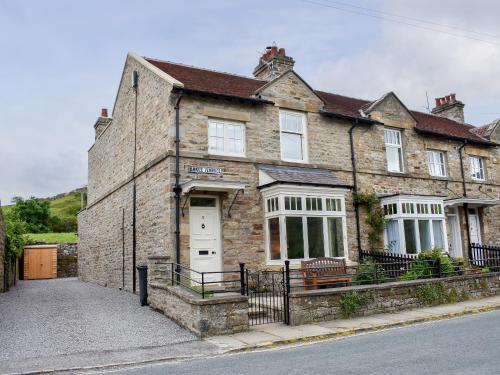an old brick house with a white door and windows at Arkle Terrace in Reeth