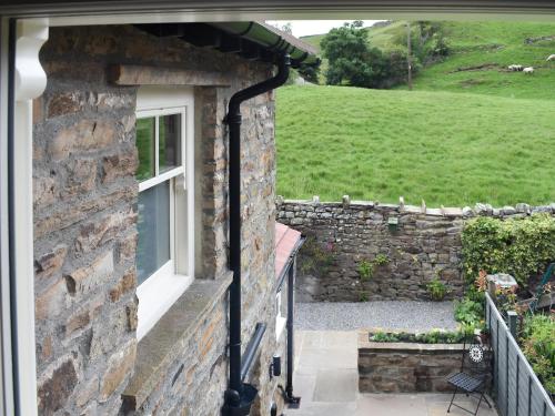 a stone house with a window and a stone wall at Arkle Terrace in Reeth