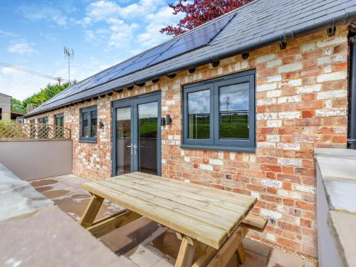 a wooden picnic table in front of a brick building at The Old Stables 1 - Uk46682 in Shipton under Wychwood