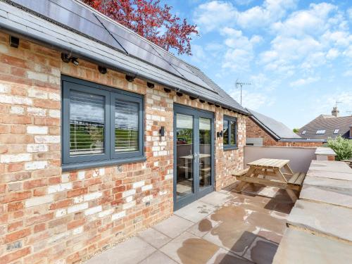 a brick house with a patio and a picnic table at The Old Stables 1 - Uk46682 in Shipton under Wychwood