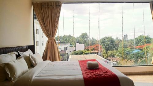 a bed in a room with a large window at Hotel Amulya Royal Inn in Bangalore