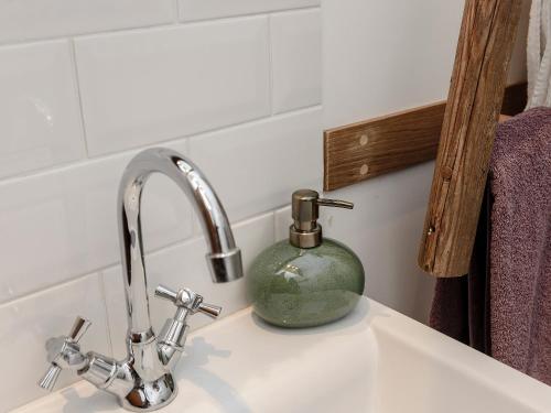 a soap dispenser sitting on a sink next to a faucet at Brook Farm Annex in Tenterden