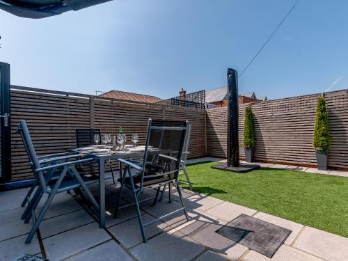 a patio with a table and chairs on a lawn at Nursery Mews in Whitstable