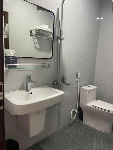 a white bathroom with a sink and a toilet at Nhà Nghỉ Thuận Phát in Làng Chang