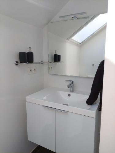 a white bathroom with a sink and a mirror at Appartement meublé Tilff in Esneux