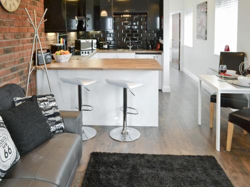 a living room with a couch and a kitchen at Oswald Lodge in Llanon