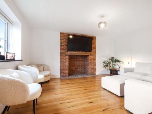 a living room with white furniture and a brick fireplace at Chancery View in Ross on Wye