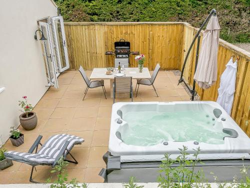 a hot tub on a patio with a table and chairs at Wits End Cottage in Martin