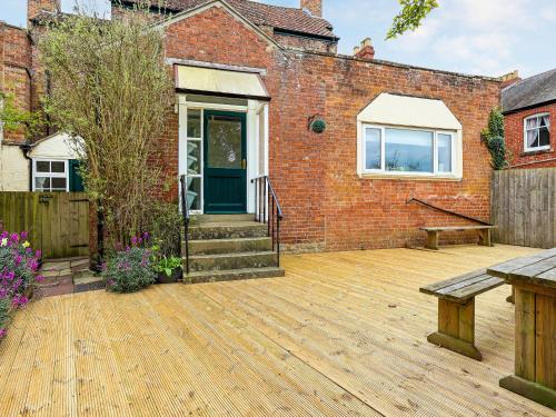 a brick house with a wooden patio with a bench at Brook House - Uk43013 in Berkeley