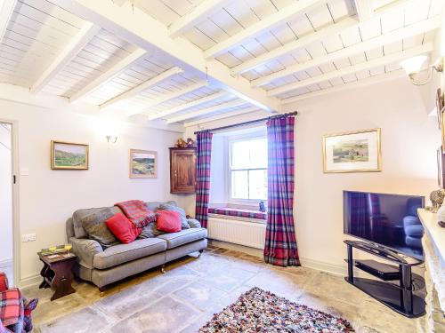 a living room with a couch and a tv at Ghyll View in Gunnerside