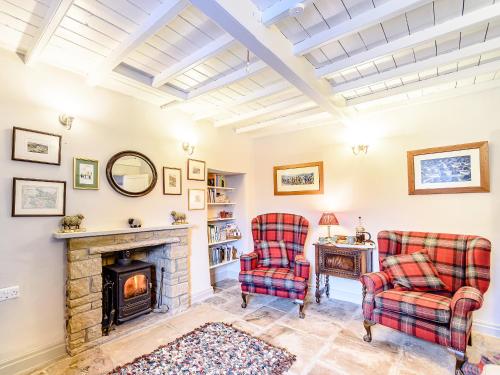a living room with two chairs and a fireplace at Ghyll View in Gunnerside
