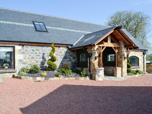 a stone house with a gambrel roof at Hillend Stables in Dalry