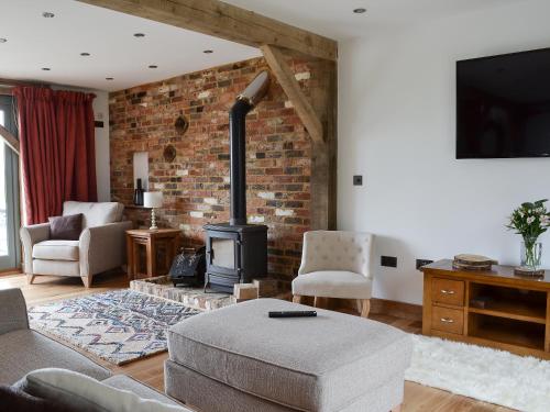 a living room with a brick wall and a wood stove at Henry-Oscar House in Winchelsea