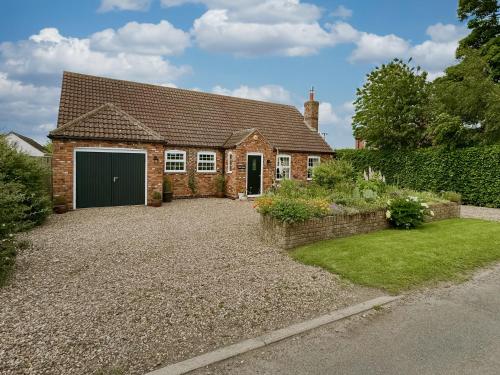 a brick house with a garage and a driveway at Lilium Cottage in North Somercotes