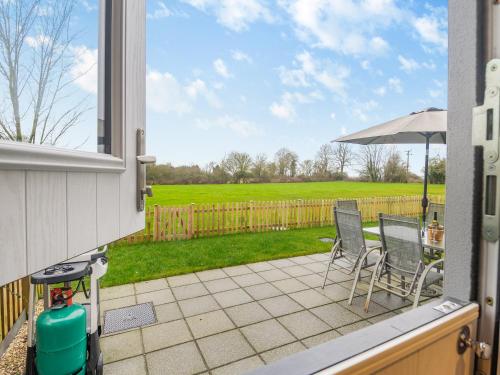 a patio with chairs and an umbrella and a fence at Walcot House Stables in Diss