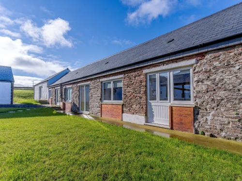 a brick building with windows and a grass yard at The Stables - Uk32514 in Marloes