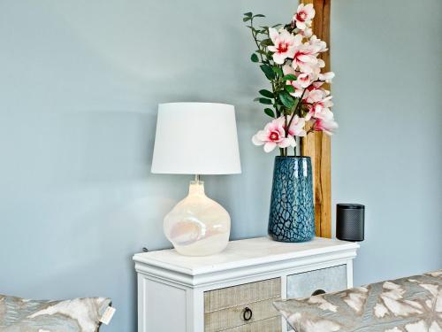 a table with a lamp and a vase with flowers on it at Woodland View Lodge in Axminster