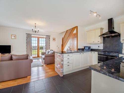 a kitchen with white cabinets and a living room at Daflod - Uk48256 in Chwilog