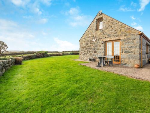 a stone barn with a picnic table in the grass at Daflod - Uk48256 in Chwilog