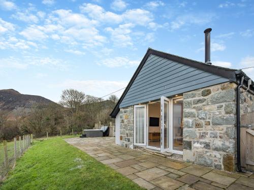 a stone cottage with a patio in the grass at Y Beudy Gwydir in Trevor