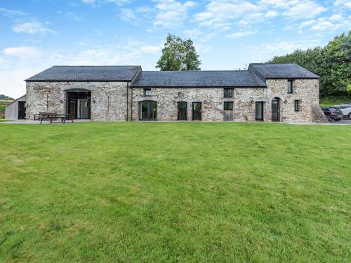 an old stone house with a large grass field at Y Stabl in Llangadog