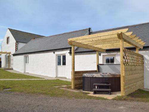 a wooden pergola next to a white building at The Cowshed - Uk32570 in Marloes