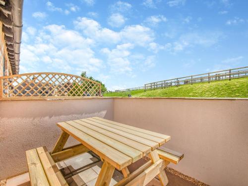 a picnic table on a balcony with a view of a hill at The Old Stables 2 - Uk46683 in Shipton under Wychwood