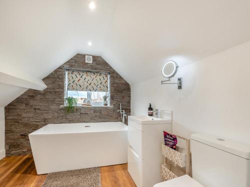 a bathroom with a white tub and a brick wall at Beachey View - Uk43058 in Saundersfoot