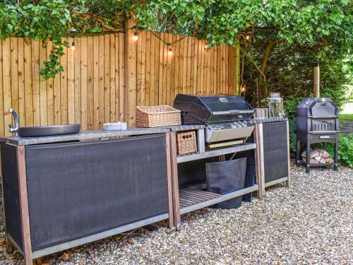 a grill and smoker in a yard next to a fence at Greenbank Cottage in Burley