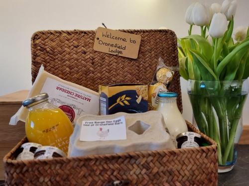 a basket with food and drinks and a vase of flowers at Dronefield Lodge in Pitney
