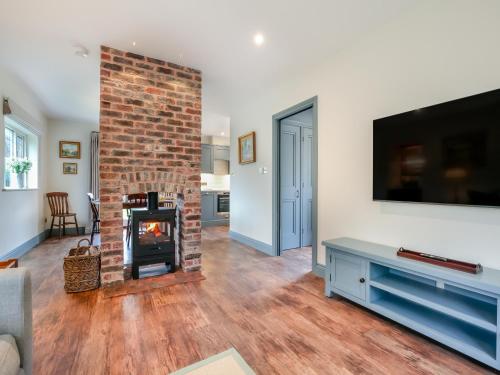 a living room with a fireplace and a flat screen tv at Keeds Cottage in Pulborough