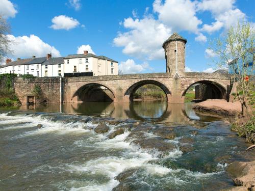 a stone bridge over a river with waterfalls at The Lodge in Wonastow