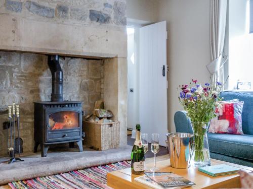 a living room with a fireplace and a table with wine bottles at The Old Cottage - Uk49169 in Beadnell