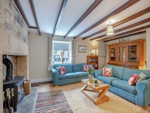 a living room with blue couches and a fireplace at The Old Cottage - Uk49169 in Beadnell