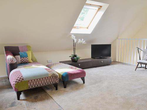 a living room with a chair and a tv at Forest Cottage in Northwold