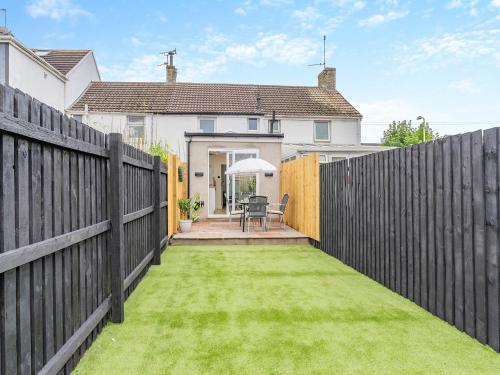 a backyard with a fence and a lawn at Wick Cottage in Nottage